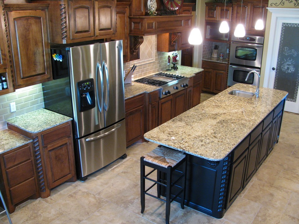 Kitchen with island and stainless steel refrigerator